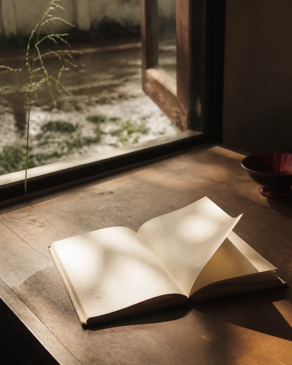 Livro aberto junto a uma janela, com luz natural e sombras sobre as páginas